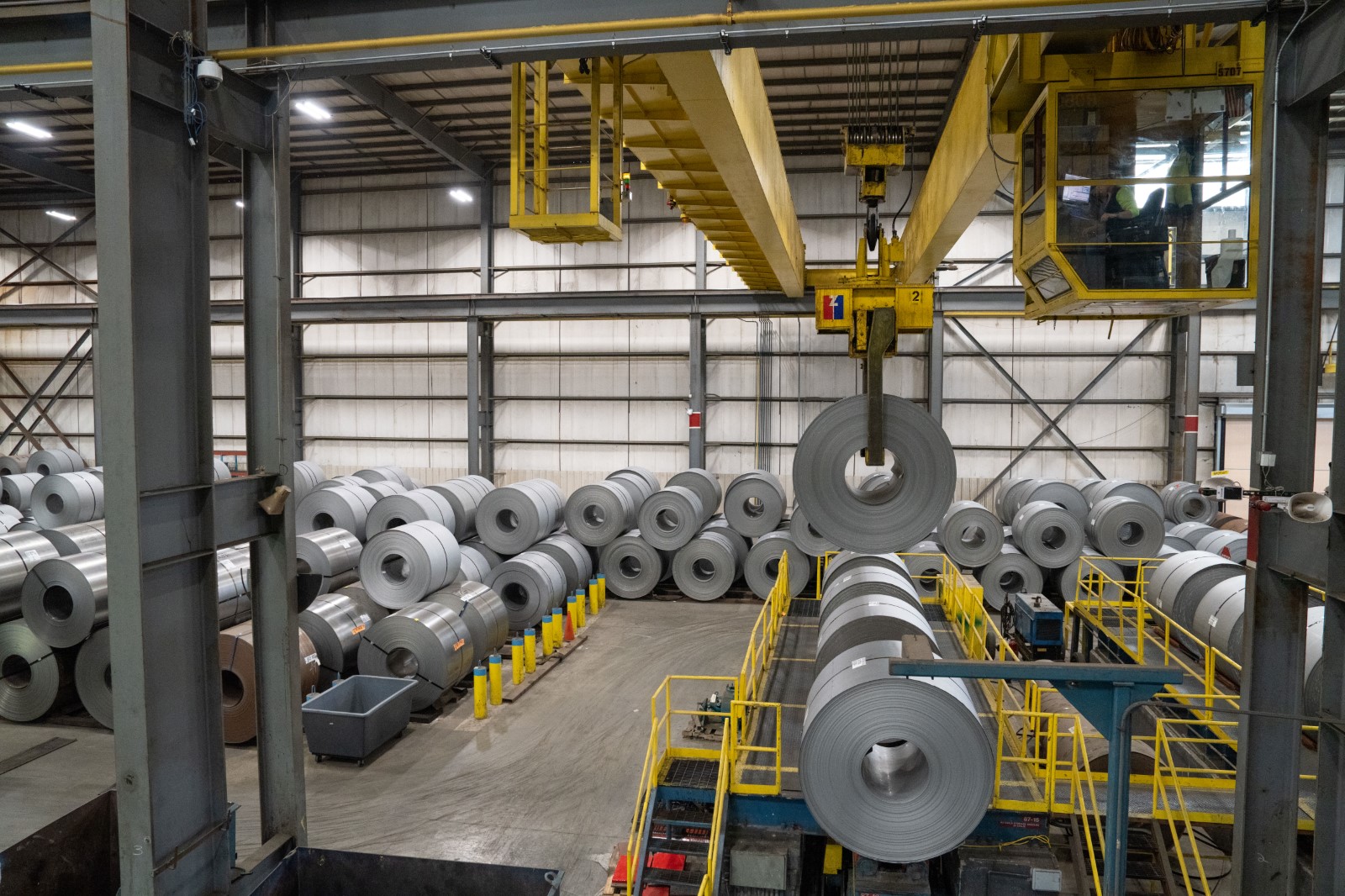 Crane moving a flat rolled steel coil through the bay at a Worthington steel processing facility.